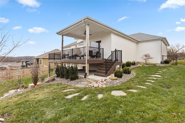 rear view of house featuring a lawn, ceiling fan, and a wooden deck