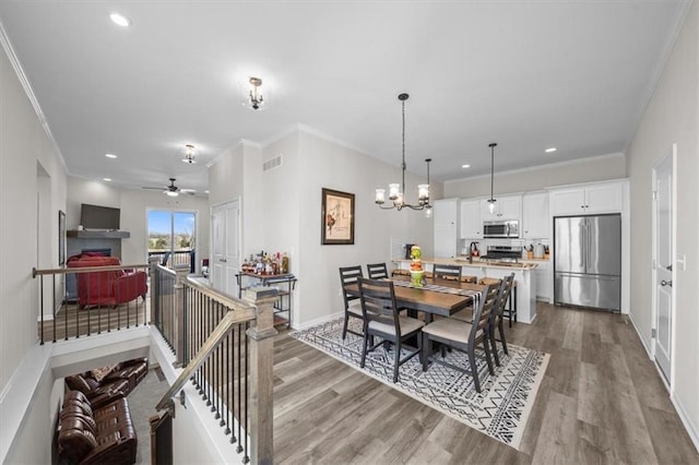 dining room featuring a notable chandelier, ornamental molding, and light wood-type flooring