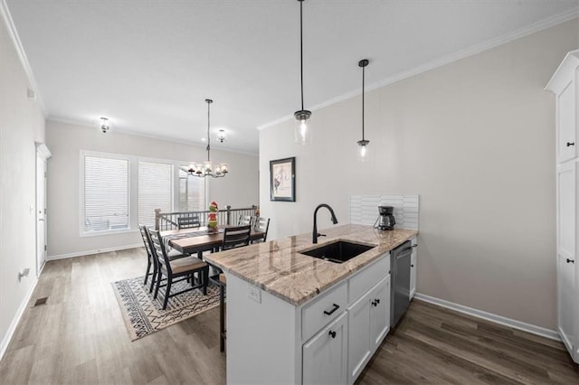 kitchen featuring light stone counters, pendant lighting, sink, and white cabinets