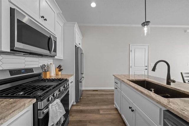 kitchen featuring decorative light fixtures, sink, white cabinets, stainless steel appliances, and light stone countertops