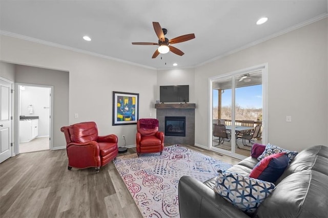 living room featuring ornamental molding, hardwood / wood-style floors, ceiling fan, and a fireplace