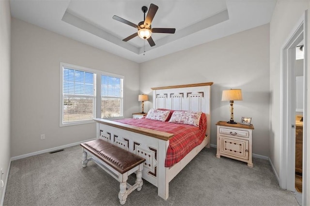 bedroom with carpet floors, ceiling fan, and a tray ceiling