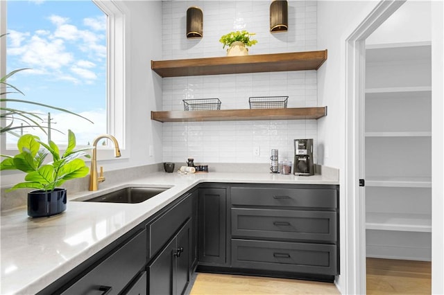 bar featuring decorative backsplash, sink, and light hardwood / wood-style floors