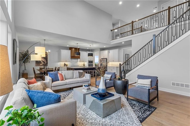 living room featuring a towering ceiling, light hardwood / wood-style floors, and sink