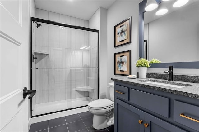 bathroom with tile patterned flooring, vanity, toilet, and a shower with door