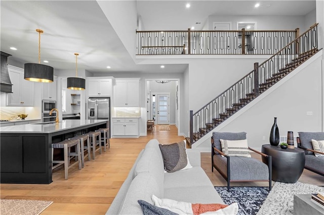 living room featuring sink, light hardwood / wood-style floors, and a high ceiling