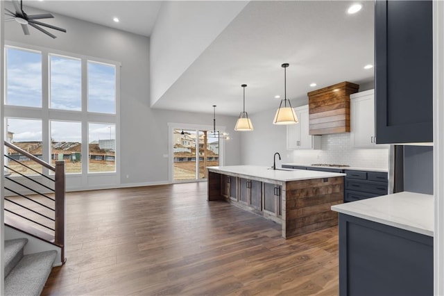 kitchen with dark wood-style floors, an island with sink, decorative light fixtures, and a ceiling fan