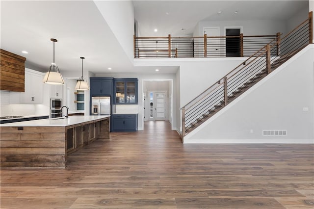 kitchen featuring decorative light fixtures, stainless steel appliances, light countertops, glass insert cabinets, and blue cabinets