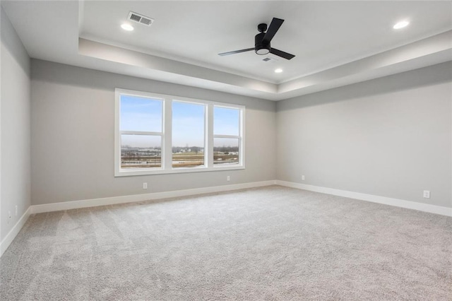 empty room with recessed lighting, a raised ceiling, visible vents, and baseboards