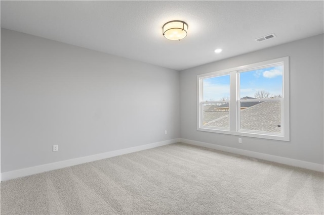 spare room with carpet floors, visible vents, and baseboards