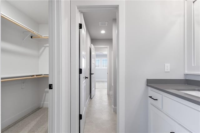 bathroom with visible vents, a spacious closet, vanity, and baseboards