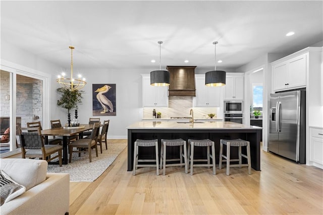 kitchen featuring premium range hood, light wood-style flooring, a sink, stainless steel appliances, and light countertops