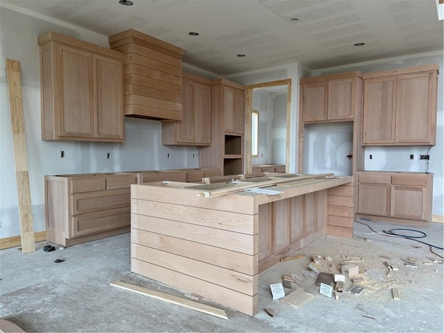 kitchen featuring baseboards, a center island, and light brown cabinets