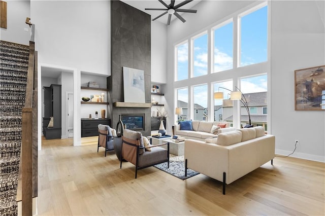 living room featuring a ceiling fan, light wood-style floors, and a fireplace