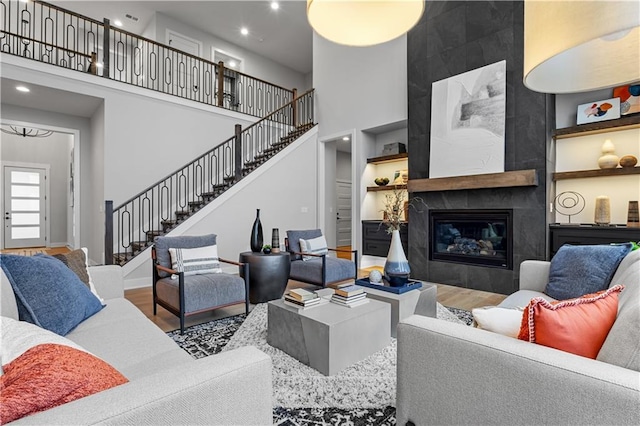 living area with stairs, wood finished floors, and a towering ceiling