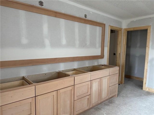 kitchen with light brown cabinetry and a textured ceiling