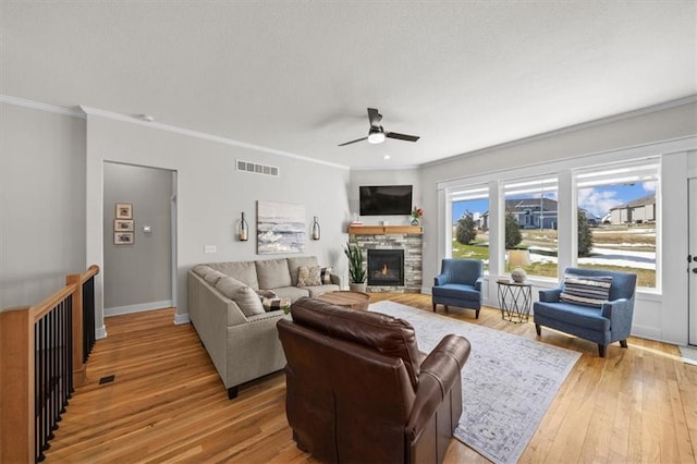 living room featuring crown molding, a fireplace, light hardwood / wood-style floors, and ceiling fan