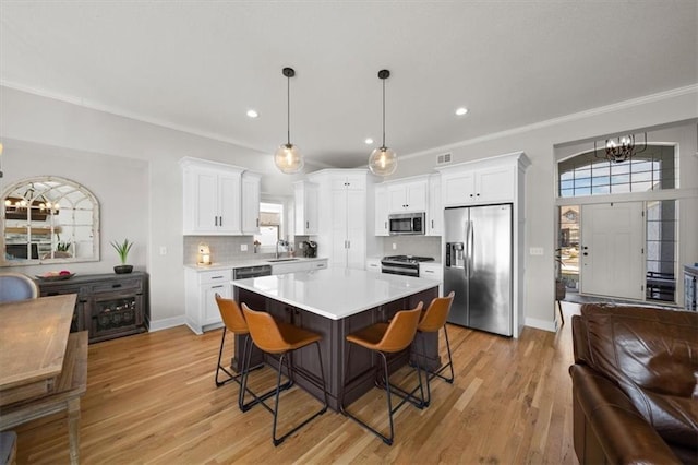 kitchen featuring pendant lighting, sink, stainless steel appliances, white cabinets, and decorative backsplash