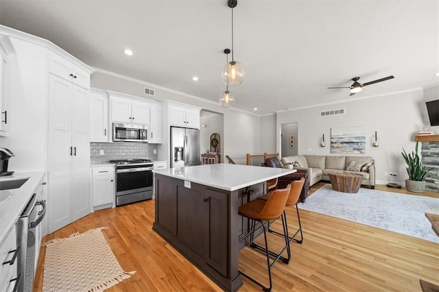 kitchen featuring white cabinetry, stainless steel appliances, hanging light fixtures, and a kitchen island