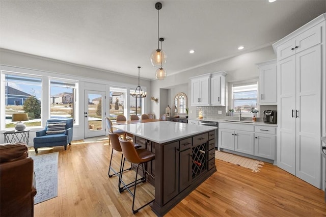 kitchen featuring white cabinetry, hanging light fixtures, a center island, and dishwasher