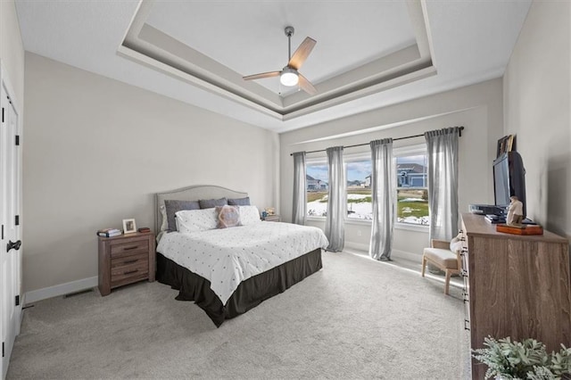 carpeted bedroom featuring a tray ceiling and ceiling fan