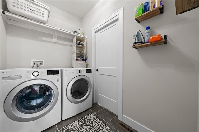 washroom with dark tile patterned flooring and washer and clothes dryer