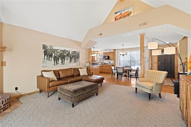 living room with decorative columns, high vaulted ceiling, and a chandelier