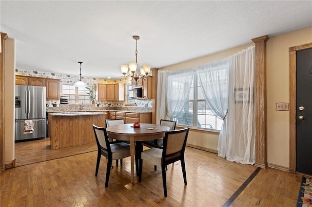 dining space featuring light hardwood / wood-style floors, a healthy amount of sunlight, and an inviting chandelier