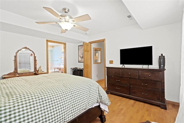 bedroom featuring ceiling fan, light hardwood / wood-style flooring, and connected bathroom