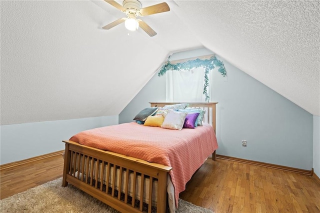 bedroom with ceiling fan, hardwood / wood-style floors, vaulted ceiling, and a textured ceiling