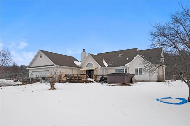 snow covered back of property featuring a hot tub and a wooden deck