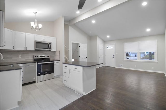 kitchen with white cabinets, sink, hanging light fixtures, appliances with stainless steel finishes, and beam ceiling