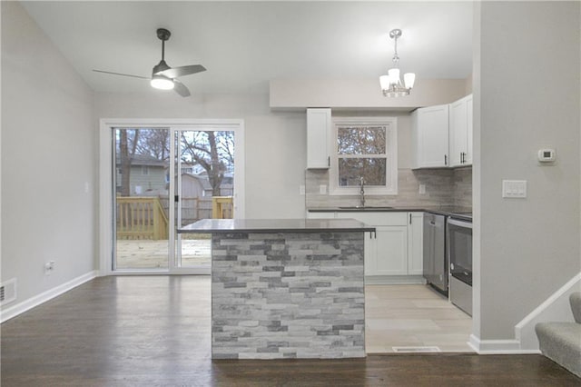 kitchen with white cabinetry, sink, pendant lighting, decorative backsplash, and range