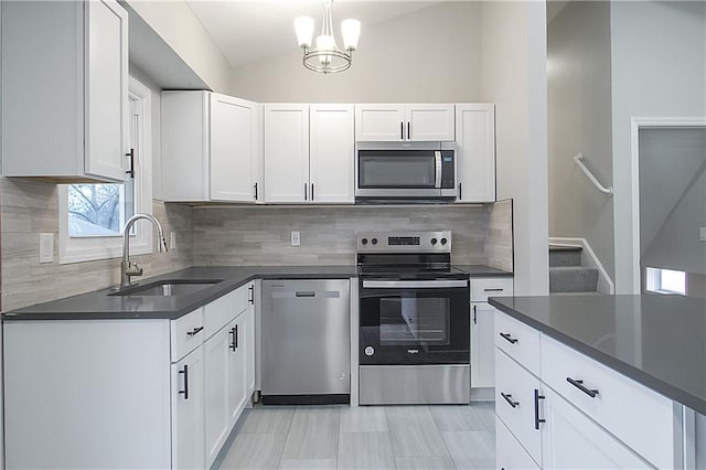 kitchen featuring white cabinets, stainless steel appliances, vaulted ceiling, and sink