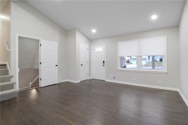 foyer entrance with dark wood-type flooring and vaulted ceiling