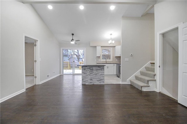 unfurnished living room featuring dark hardwood / wood-style flooring, sink, high vaulted ceiling, and ceiling fan with notable chandelier