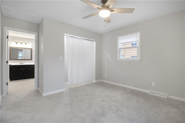 unfurnished bedroom with ceiling fan, sink, light colored carpet, and ensuite bathroom