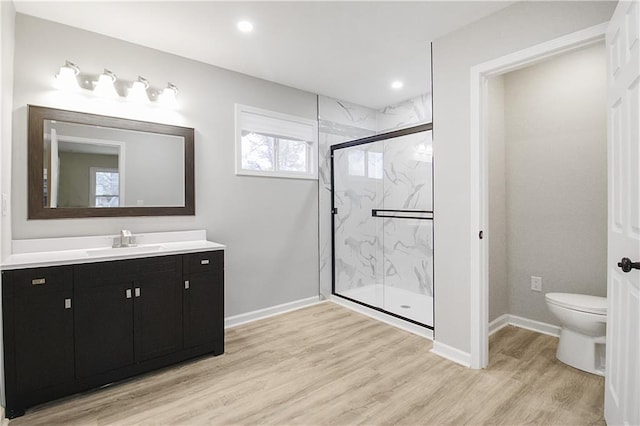 bathroom featuring a shower with door, vanity, wood-type flooring, and toilet