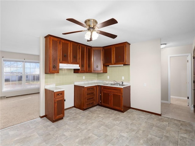 kitchen featuring tasteful backsplash, ceiling fan, sink, and light colored carpet