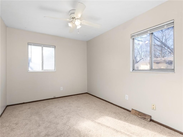 empty room featuring ceiling fan, light colored carpet, and plenty of natural light