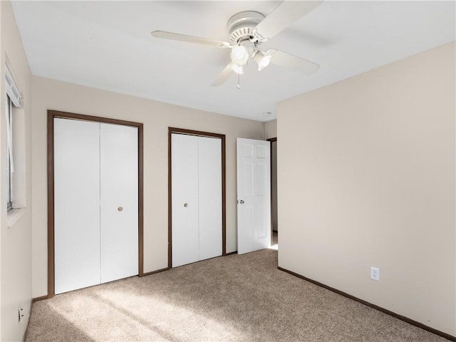 unfurnished bedroom featuring multiple closets, ceiling fan, and light carpet