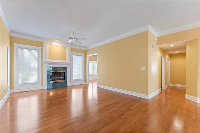 unfurnished living room with ornamental molding, a high end fireplace, a wealth of natural light, and light wood-type flooring