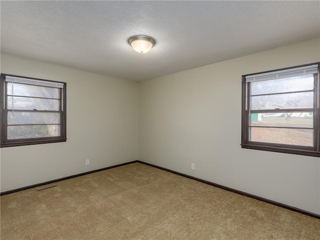 empty room featuring a textured ceiling and light carpet