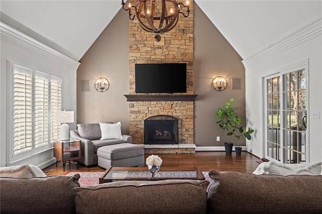 living room featuring vaulted ceiling, a healthy amount of sunlight, a fireplace, and a notable chandelier