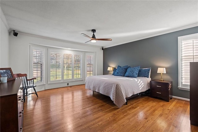 bedroom featuring ceiling fan, multiple windows, and ornamental molding