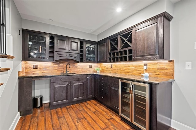 bar with wine cooler, decorative backsplash, sink, and stone countertops