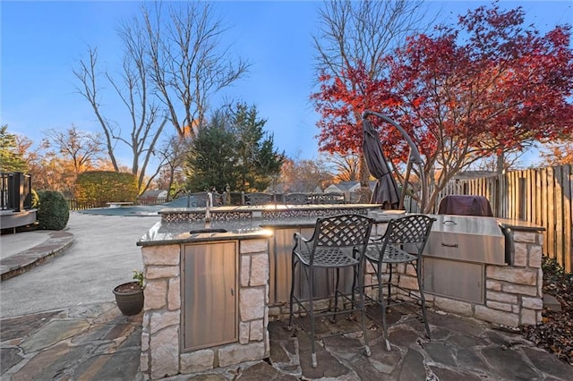 view of patio with an outdoor kitchen, a covered pool, and an outdoor bar