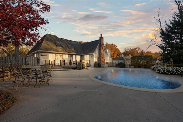 pool at dusk featuring a patio area and a wooden deck