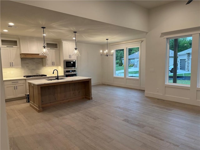 9301 SW Leviathan Ct, Lees Summit, MO 64064 - kitchen featuring stainless steel appliances, a sink, a chandelier, backsplash, and light wood-style floors