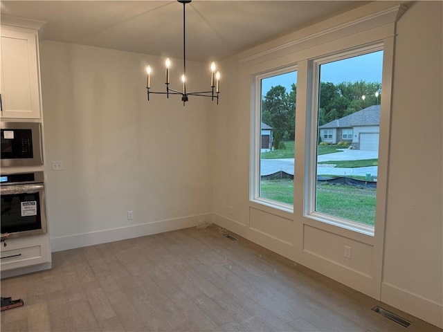 9301 SW Leviathan Ct, Lees Summit, MO 64064 - unfurnished dining area featuring a chandelier, light wood-type flooring, and baseboards
